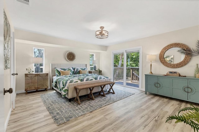 bedroom with light wood finished floors, multiple windows, and access to exterior
