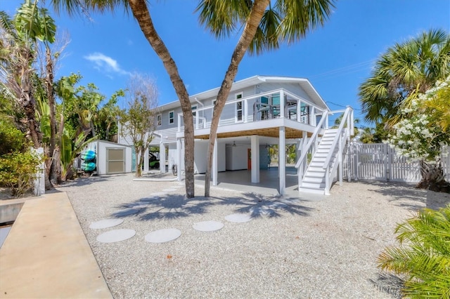 view of front of property with stairs, an outdoor structure, a shed, a carport, and gravel driveway