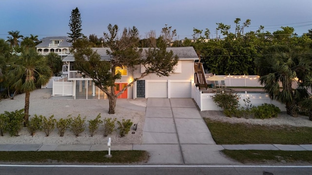 view of front facade with stairs, a garage, fence, and concrete driveway