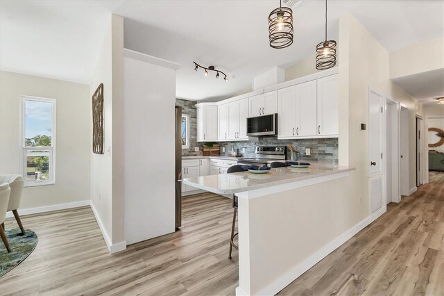 501 Key Royale Dr, Holmes Beach, FL 34217 - kitchen featuring appliances with stainless steel finishes, decorative backsplash, light wood-style flooring, light countertops, and white cabinetry