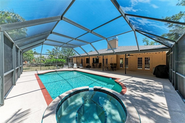 view of swimming pool with a ceiling fan, french doors, a pool with connected hot tub, glass enclosure, and a patio