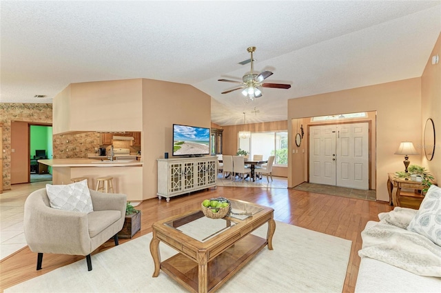 living room featuring light wood-style floors, ceiling fan, vaulted ceiling, and visible vents