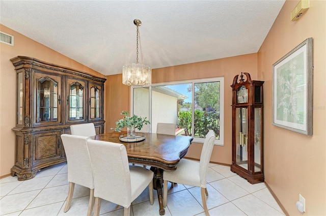 dining space featuring light tile patterned floors, a textured ceiling, and a notable chandelier