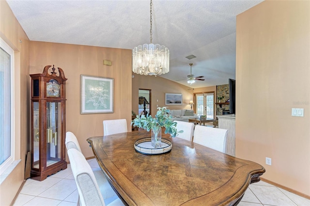 dining room featuring a textured ceiling, vaulted ceiling, light tile patterned floors, and ceiling fan with notable chandelier