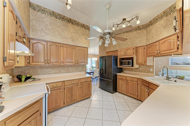kitchen featuring black refrigerator with ice dispenser, stainless steel microwave, under cabinet range hood, a sink, and range