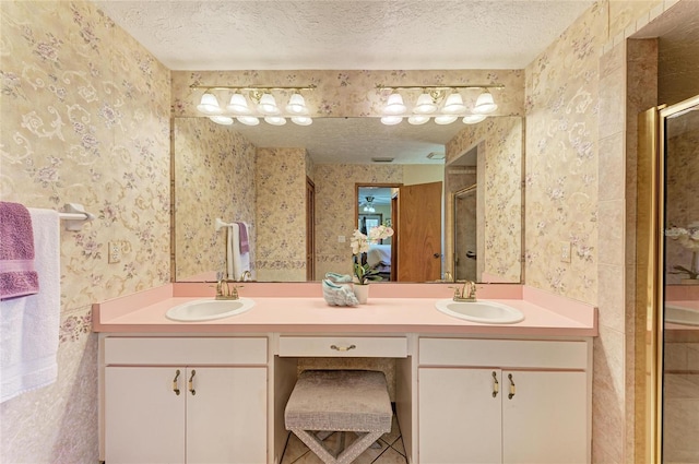 full bath with a sink, a shower stall, and wallpapered walls