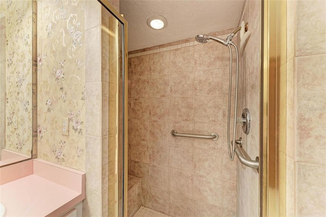 full bath with vanity, a shower stall, wallpapered walls, and a textured ceiling
