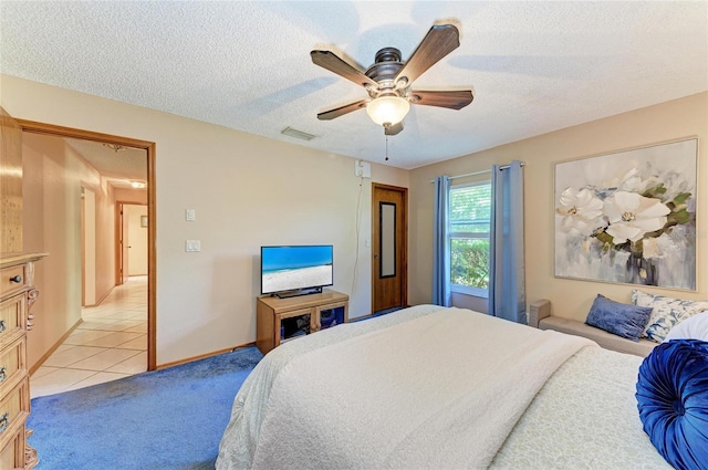 bedroom featuring light tile patterned flooring, light colored carpet, a textured ceiling, a ceiling fan, and visible vents