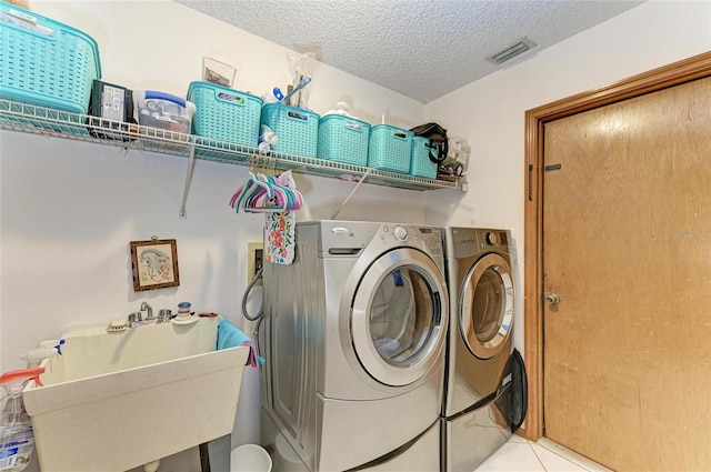 laundry area featuring separate washer and dryer, laundry area, a textured ceiling, and visible vents