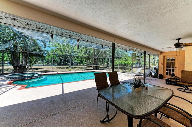 view of pool with ceiling fan, a patio area, a pool with connected hot tub, and glass enclosure