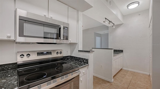 4264 Central Sarasota Pkwy Unit 111, Sarasota, FL 34238 - kitchen with stainless steel appliances, white cabinetry, light tile patterned floors, rail lighting, and baseboards
