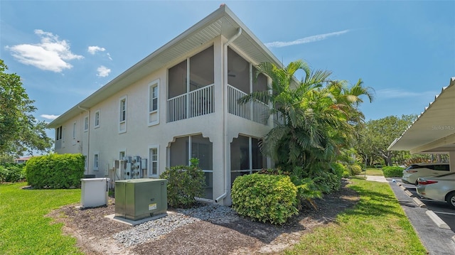 4264 Central Sarasota Pkwy Unit 111, Sarasota, FL 34238 - view of property exterior featuring stucco siding, a lawn, and a sunroom
