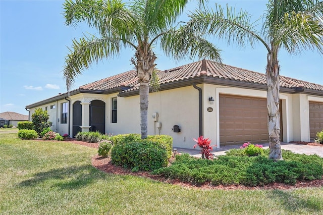 mediterranean / spanish house featuring stucco siding, a front yard, a tiled roof, and an attached garage