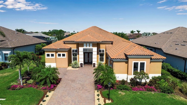 mediterranean / spanish-style house with a tile roof, stucco siding, french doors, and a front lawn