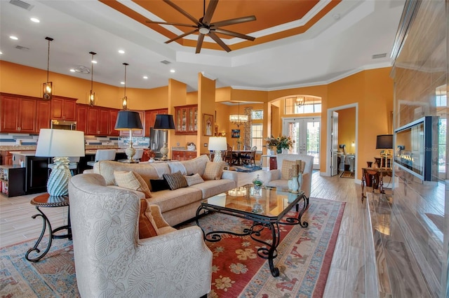 living room with arched walkways, a ceiling fan, a towering ceiling, recessed lighting, and a chandelier
