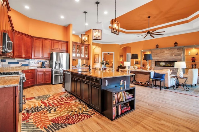 kitchen with stainless steel appliances, arched walkways, a sink, open shelves, and light wood-style floors