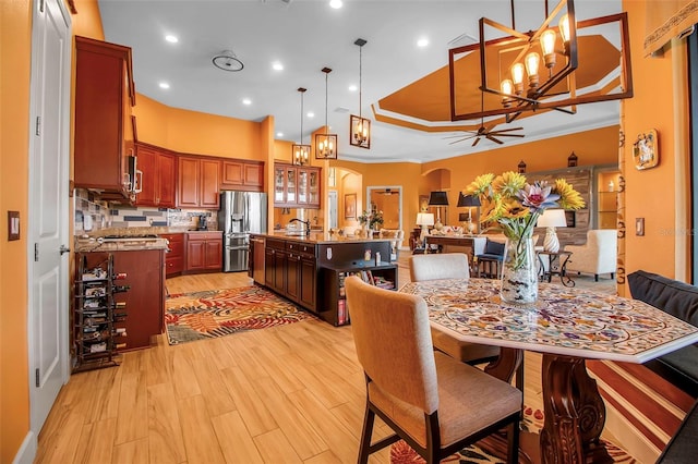 dining area with light wood-style floors, a chandelier, arched walkways, a ceiling fan, and recessed lighting