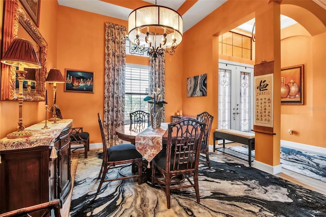 dining room with baseboards, arched walkways, and a chandelier