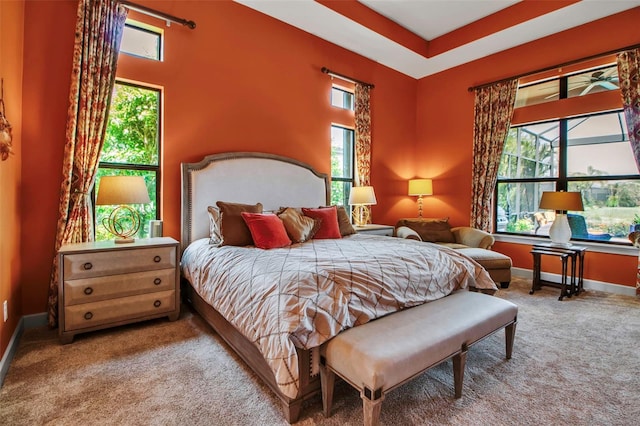 carpeted bedroom featuring multiple windows and baseboards