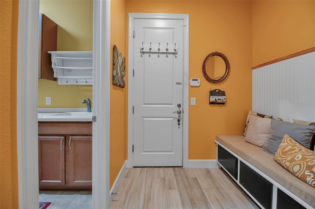 mudroom featuring a sink, baseboards, and light wood-style floors