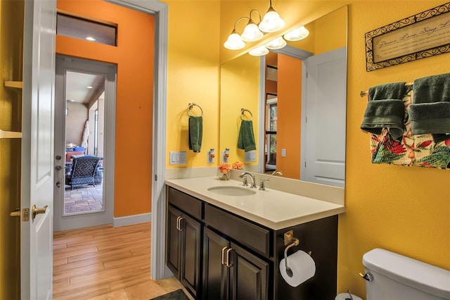 half bathroom featuring toilet, wood finished floors, and vanity