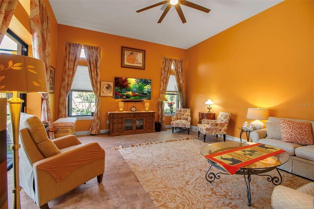 living area with ceiling fan, baseboards, and stone finish floors