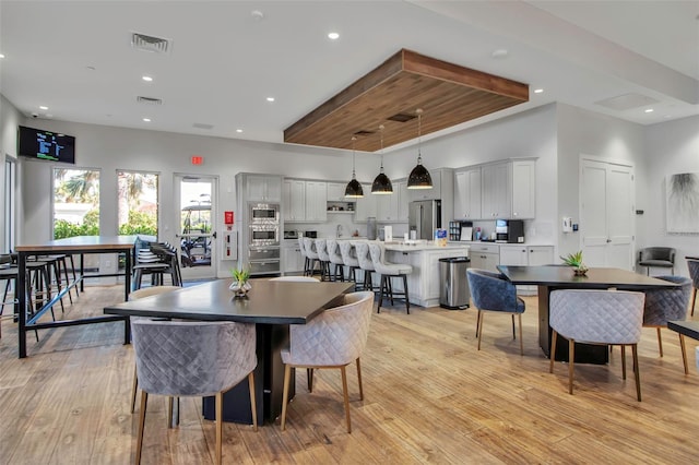 dining area with light wood finished floors, recessed lighting, and a high ceiling