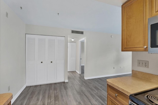 5800 Hollywood Blvd Unit 312, Sarasota, FL 34231 - kitchen featuring stainless steel microwave, brown cabinetry, wood finished floors, visible vents, and baseboards