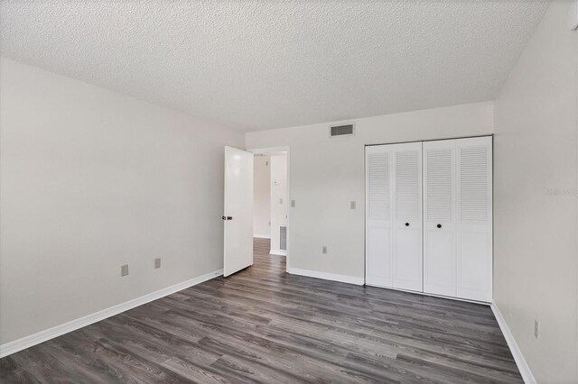 5800 Hollywood Blvd Unit 312, Sarasota, FL 34231 - unfurnished bedroom featuring a textured ceiling, visible vents, baseboards, and dark wood-type flooring