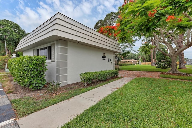 5800 Hollywood Blvd Unit 312, Sarasota, FL 34231 - view of home's exterior with stucco siding, mansard roof, an outbuilding, and a lawn