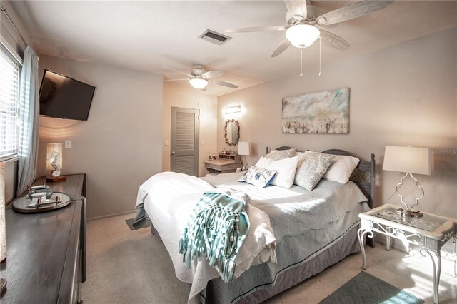 bedroom with a closet, visible vents, a ceiling fan, and light colored carpet