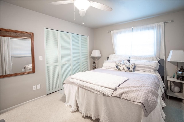bedroom with baseboards, ceiling fan, light colored carpet, and a closet