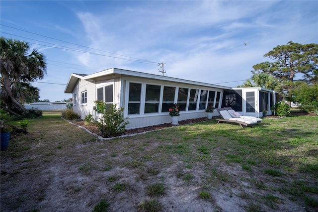rear view of house featuring a sunroom and a lawn
