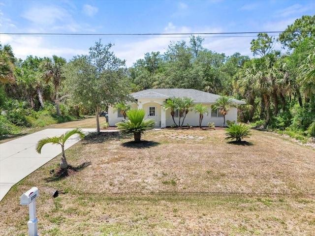 view of front of property featuring stucco siding, a front yard, and concrete driveway