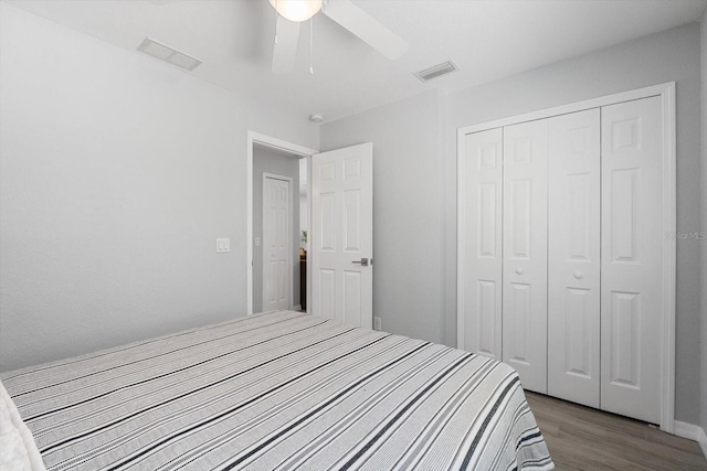 bedroom featuring ceiling fan, a closet, wood finished floors, and visible vents