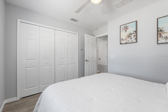 bedroom with ceiling fan, a closet, wood finished floors, and visible vents
