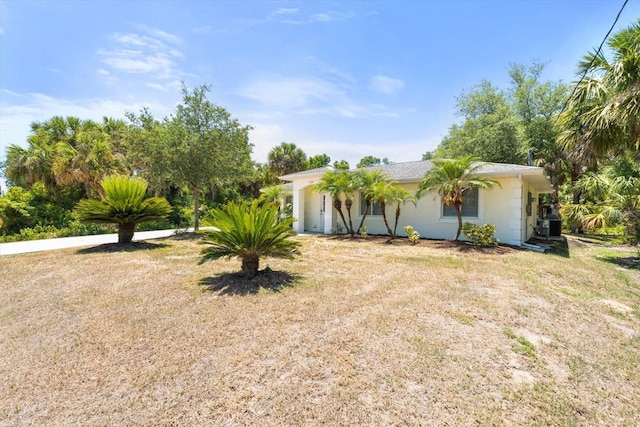 exterior space with stucco siding, a front lawn, and central AC