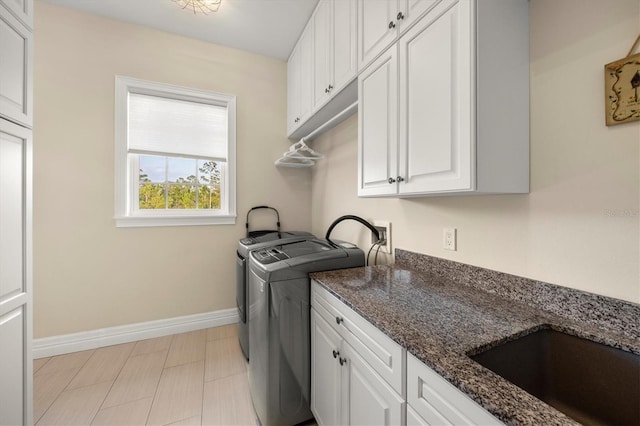 laundry room with baseboards, a sink, cabinet space, and washing machine and clothes dryer