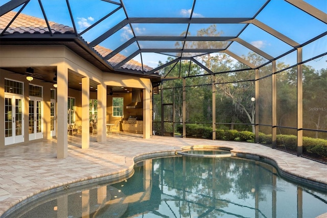 view of swimming pool featuring a ceiling fan, glass enclosure, a patio area, and a pool with connected hot tub