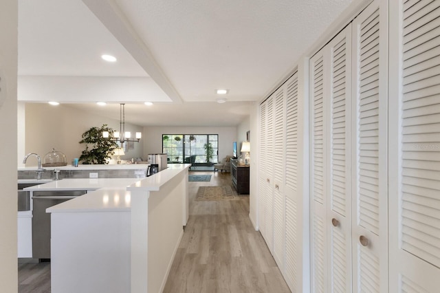 536 Lakeside Dr Unit 0, Bradenton, FL 34210 - kitchen featuring light wood-style floors, stainless steel dishwasher, light countertops, hanging light fixtures, and open floor plan