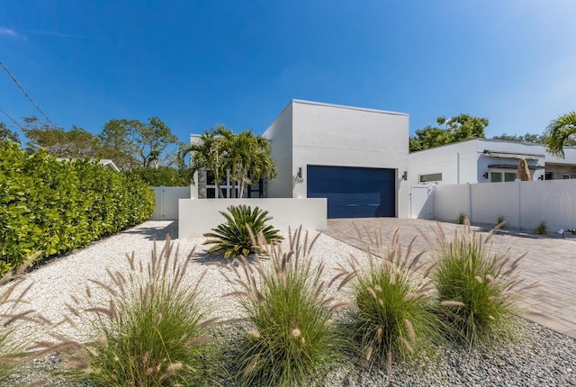 modern home featuring a gate, a fenced front yard, stucco siding, and decorative driveway