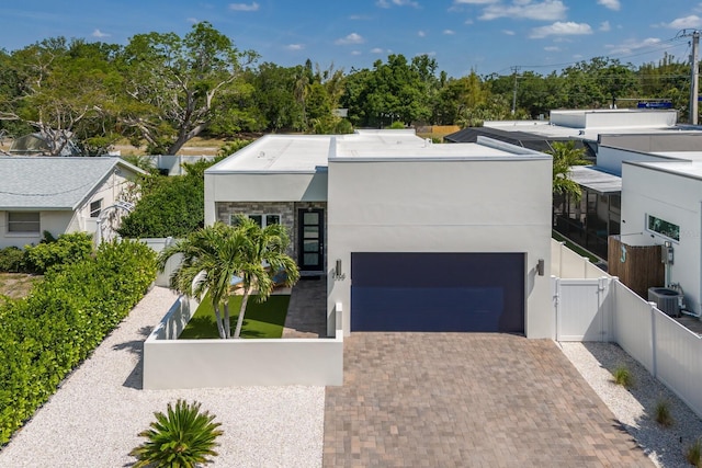 contemporary home with a gate, stucco siding, decorative driveway, fence, and a garage
