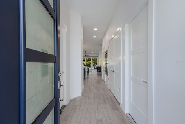 hallway with recessed lighting, light wood-style flooring, and baseboards