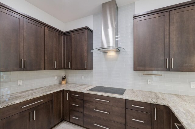 kitchen with wall chimney range hood, decorative backsplash, black electric stovetop, and dark brown cabinets