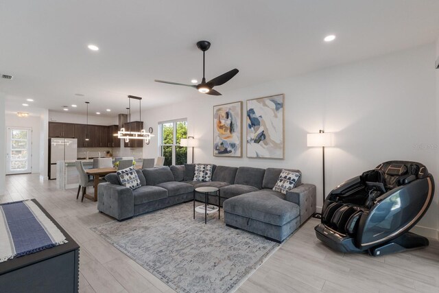 living area featuring visible vents, recessed lighting, ceiling fan with notable chandelier, and light wood-style floors
