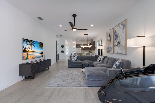 living area with visible vents, baseboards, recessed lighting, light wood finished floors, and ceiling fan with notable chandelier