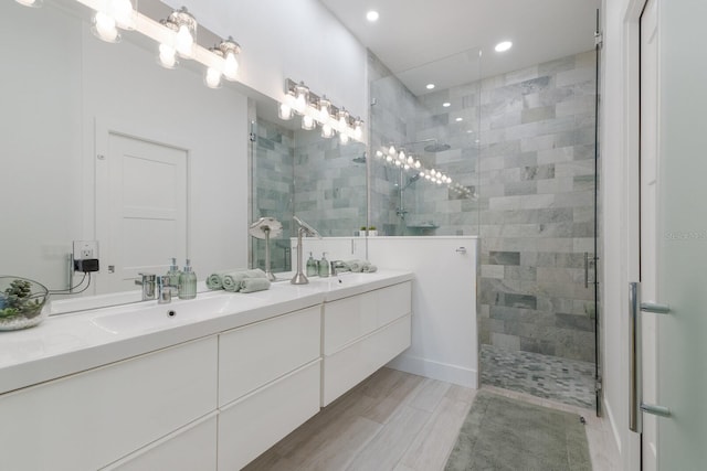 bathroom featuring double vanity, a tile shower, recessed lighting, and a sink
