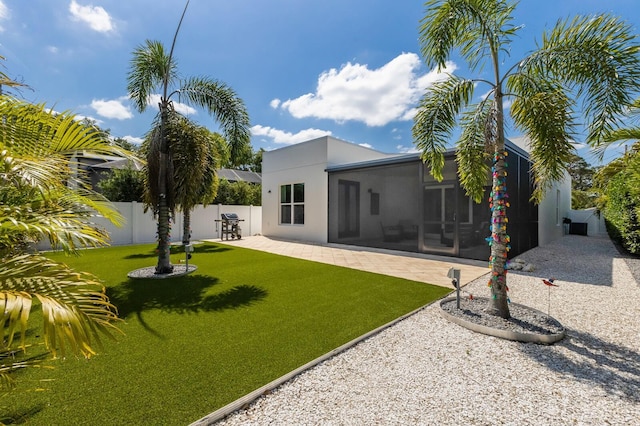 back of house featuring stucco siding, a yard, fence, a sunroom, and a patio area