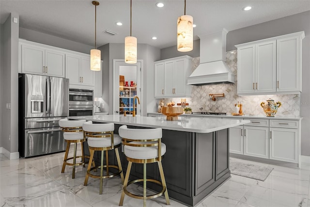 13319 Deep Blue Pl, Bradenton, FL 34211 - kitchen featuring appliances with stainless steel finishes, premium range hood, light marble finish flooring, light countertops, and tasteful backsplash
