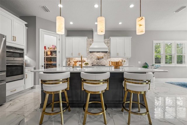 13319 Deep Blue Pl, Bradenton, FL 34211 - kitchen featuring light marble finish flooring, backsplash, light countertops, recessed lighting, and a kitchen island with sink